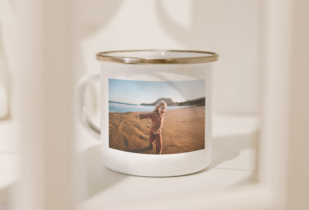 Mug émaillé blanc et doré personnalisé avec une photo d'enfant courant sur la plage.